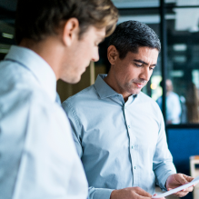 Two men in blue dress shirts reviewing an insurance document together