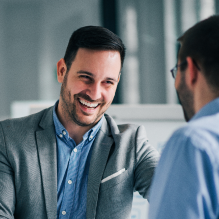 Two men in business casual wear smiling in a meeting